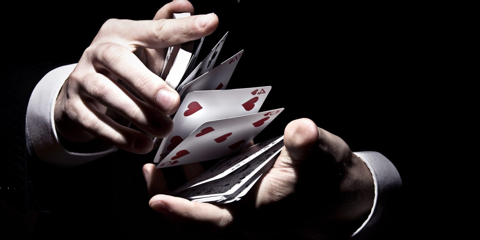 A magician shuffling the cards in a cool way under the spotlight